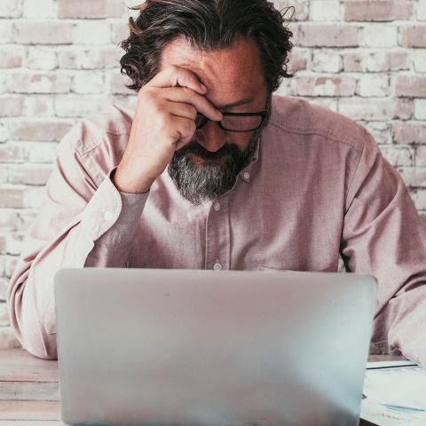 Stressed man looking at computer screen