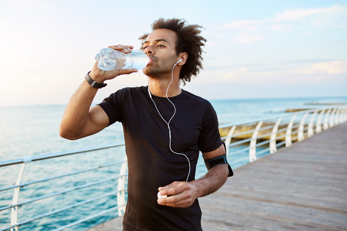 Afro American man runner drinking water cardio workout athlete fitness hydrating outdoor training 166138165 SM