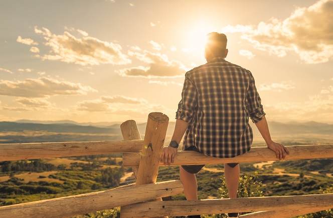 Thoughtful young man sitting on fence in peaceful nature setting outside SM 303931927