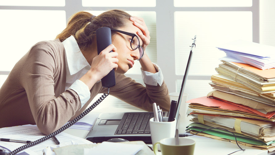 a stressed business woman looks tired she answer telephones in her office