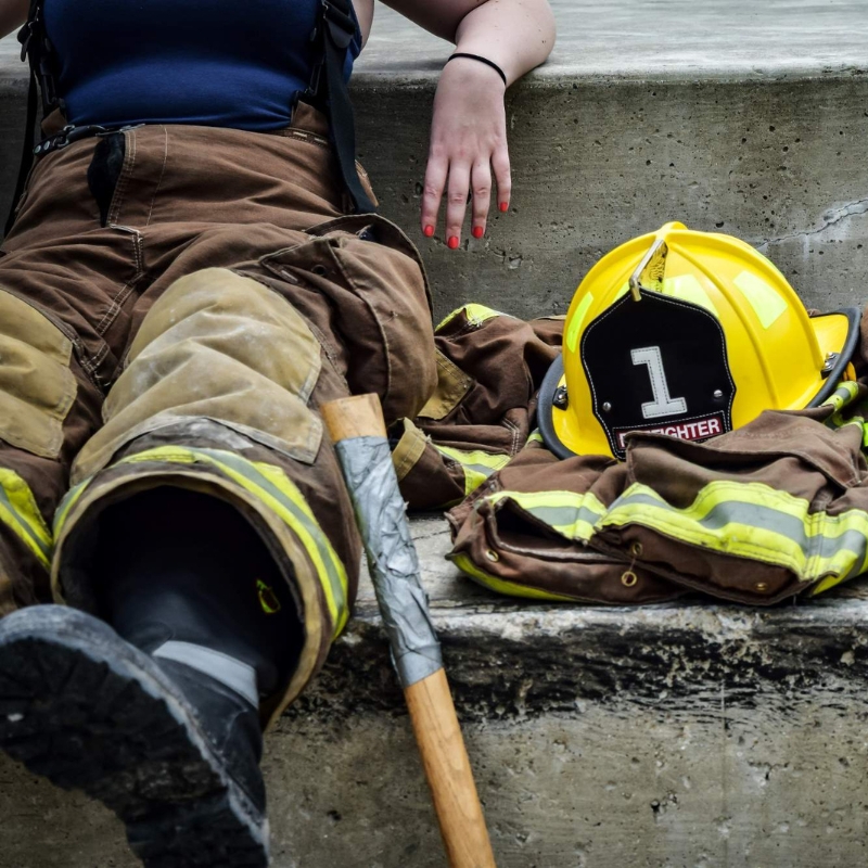 Tired female firefighter rests near her gear