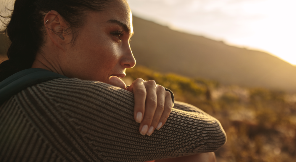 Close up of a woman deep in thought outdoors at sunset, symbolizing contemplation and mindfulness amidst anticipatory grief