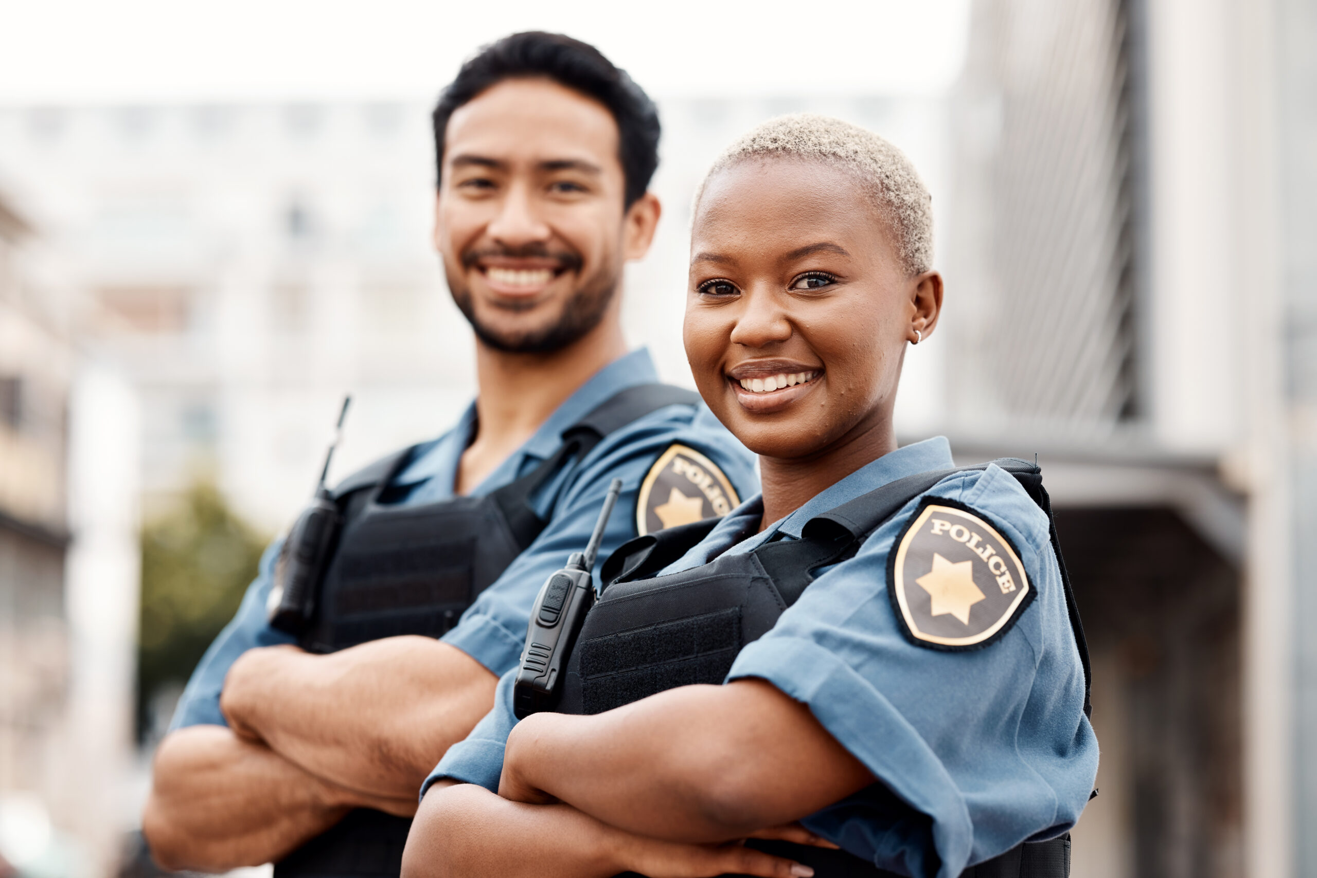 Happy police, team and arms crossed in confidence for city protection, law enforcement or crime. Portrait of man and woman officer standing ready for justice, security or teamwork in an urban town Smiling policewoman